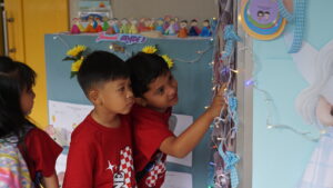 Dua orang siswa sedang mengamati hasil karya yang dipamerkan di lorong sekolah