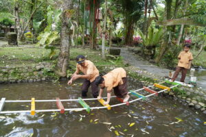 Potret seorang siswa sedang meniti jembatan balok didampingi seorang guru