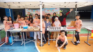 Para siswa dan guru berfoto bersama di stan kelas mereka