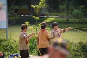 Momen ketika tiga orang siswa bekerja sama menyusun rangka untuk mendirikan tenda