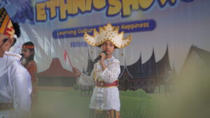 Potret seorang siswa sedang bernyanyi sembari mengibaskan Bendera Merah Putih kecil