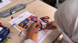 Potret terampil siswa mengoleskan lem pada gambar untuk menempelkan potongan plastik