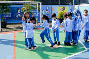 Siswa Grade 1 melompat ke kardus di depannya dalam permainan Bomb Step